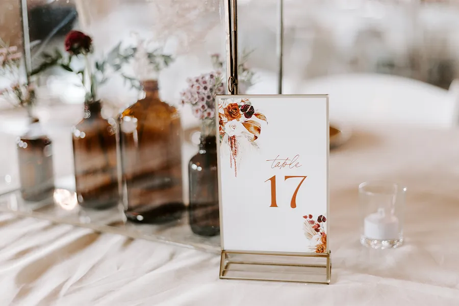 Boho table setting with amber bottles, dried florals, and a 'Table 17' card